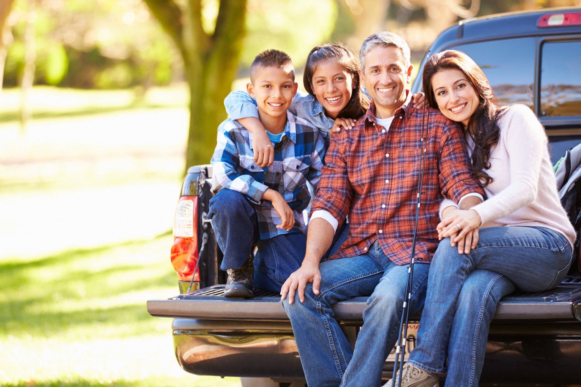 Family Sitting In Pick Up Truck On Camping Holiday