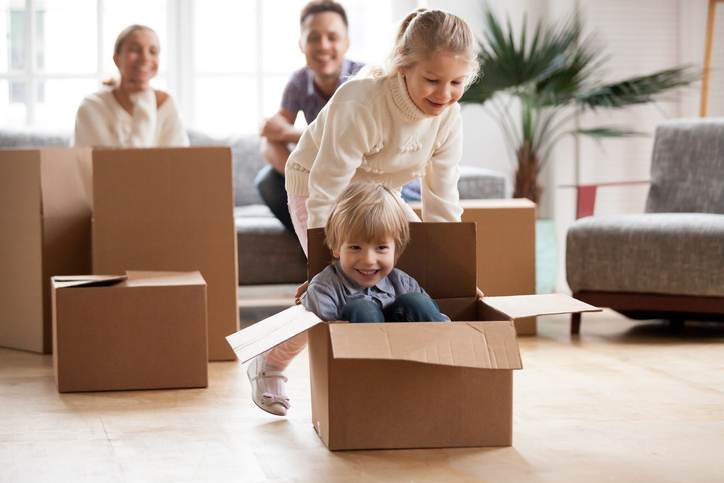 Happy siblings playing riding in box moving into new home